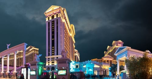An image of Caesars Palace in Las Vegas at night, lit up against the dark sky