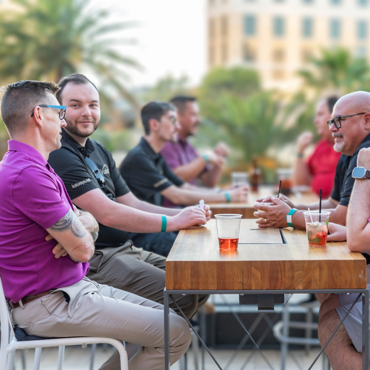 A group of colleagues smile and laugh across an outdoor picnic table