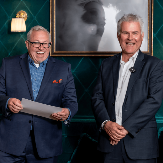 Two men standing side by side, one holding a diploma