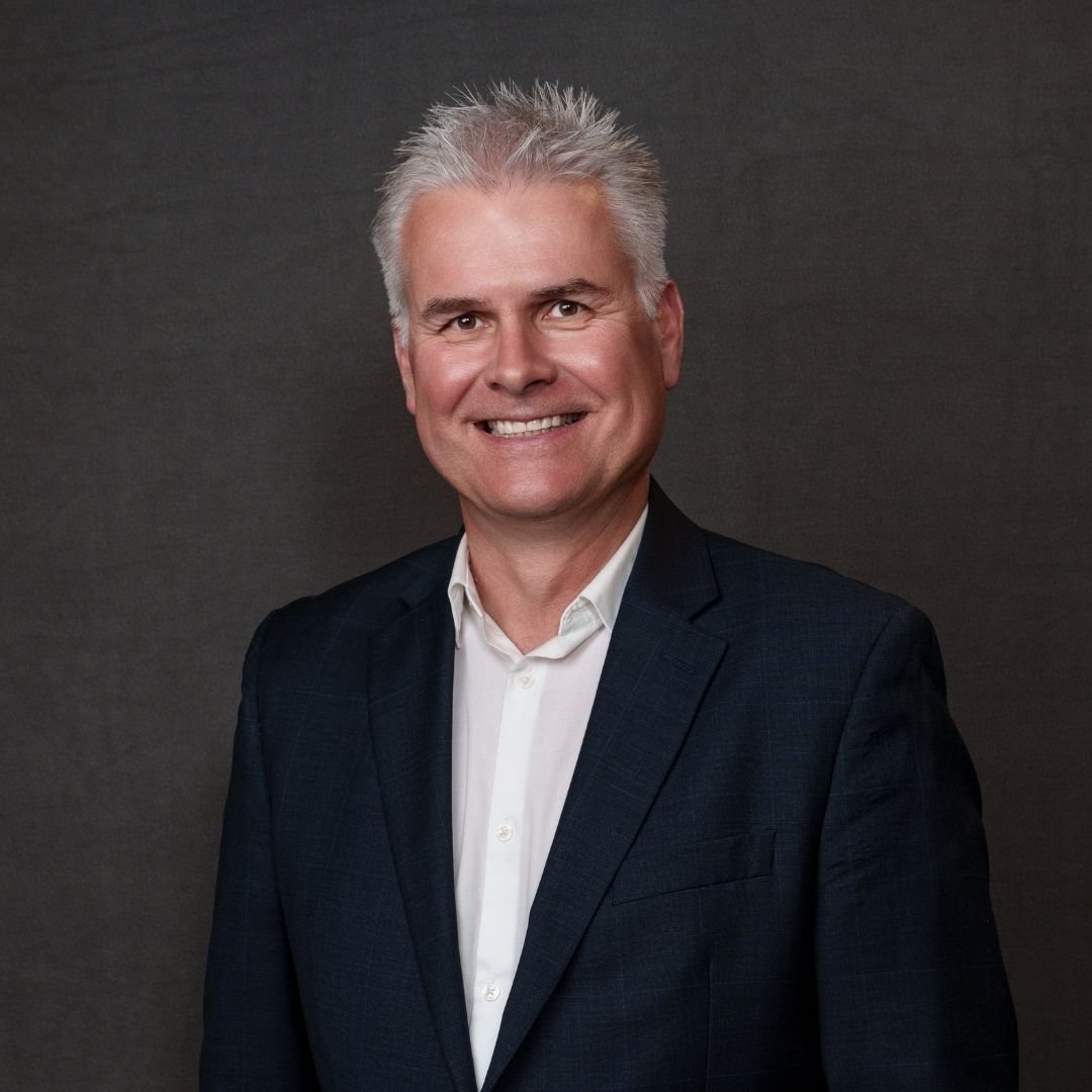 Ken Rastin, President and CEO, smiles at the camera in a dark suit