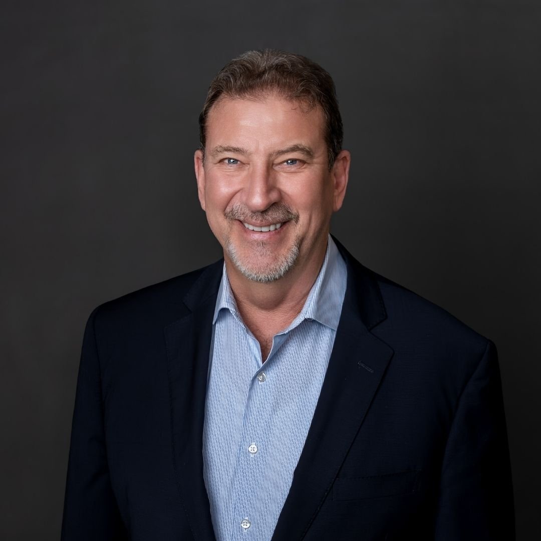 Alan R Byrum, VP of Resiliency, smiles at the camera in a black suit against a dark background