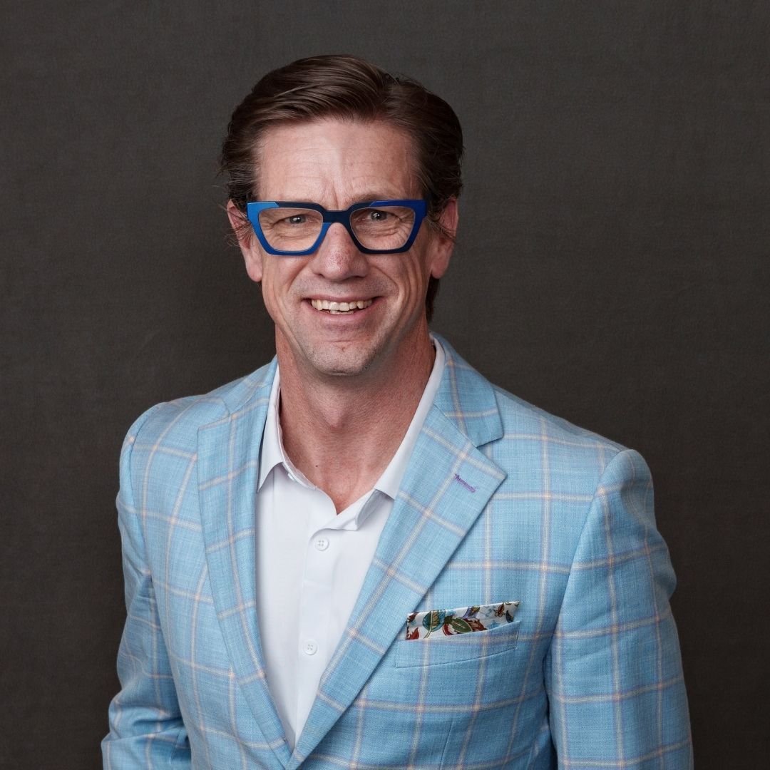 Steve Kay, Chief Resiliency Officer, smiles at the camera in a blue suit against a dark background